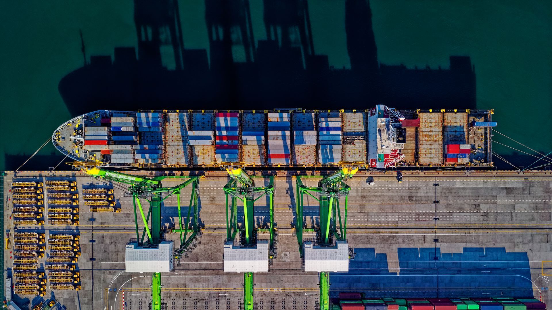 Overhead view of a container vessel beside port cranes